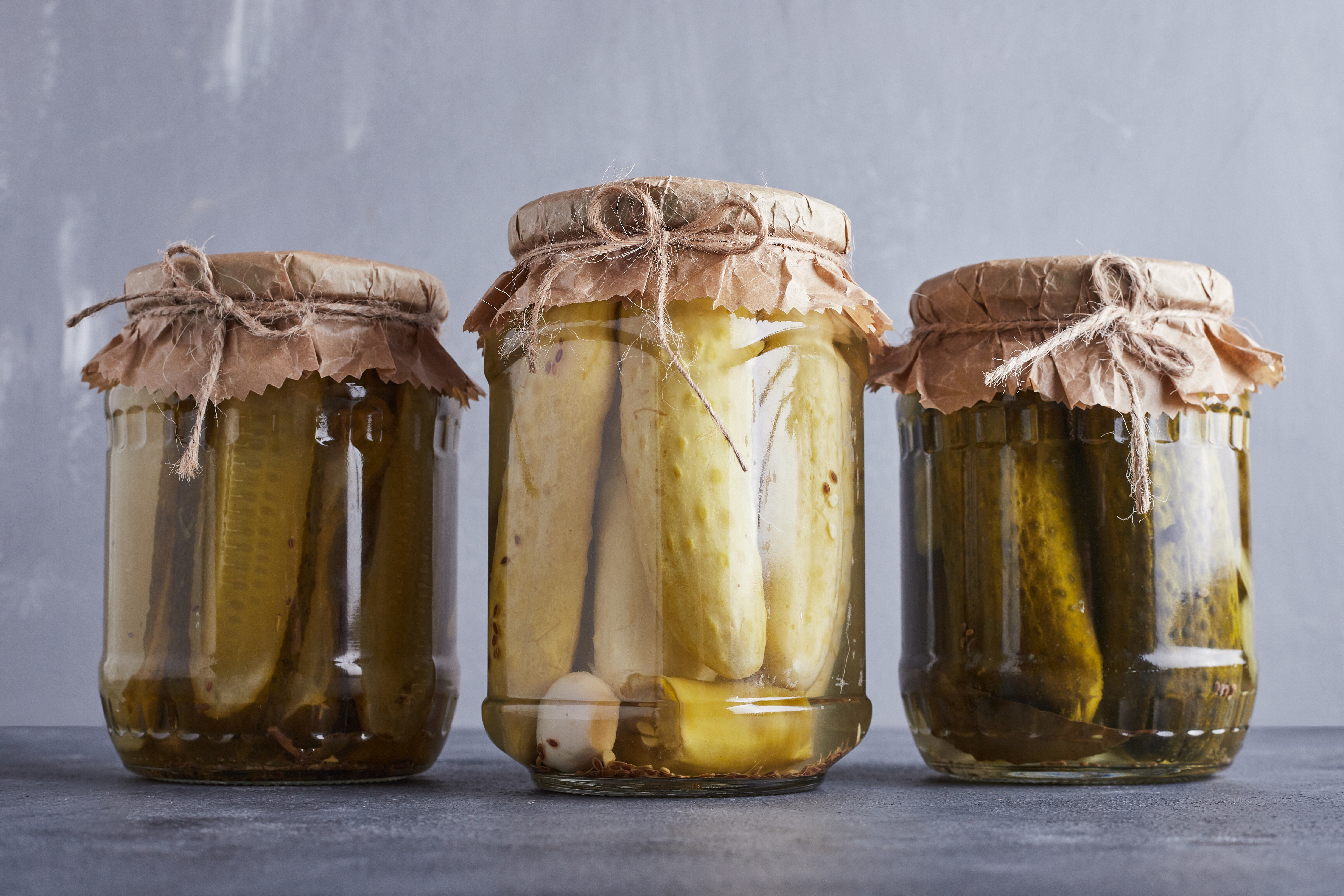 3 different jars of pickles: fermented cucumbers. The middle one is lighter in color.
