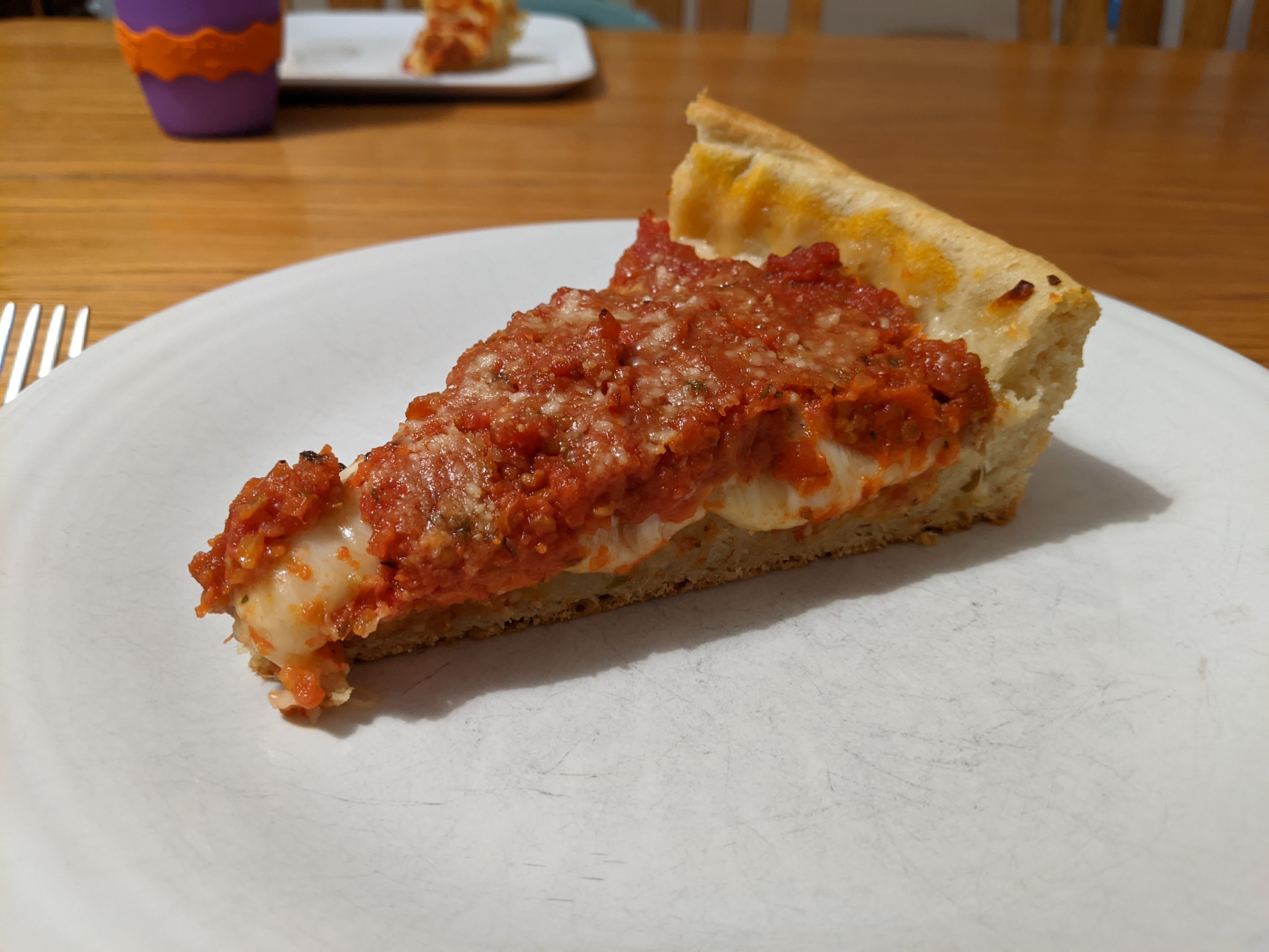 A slice of deep dish pizza on a white plate.