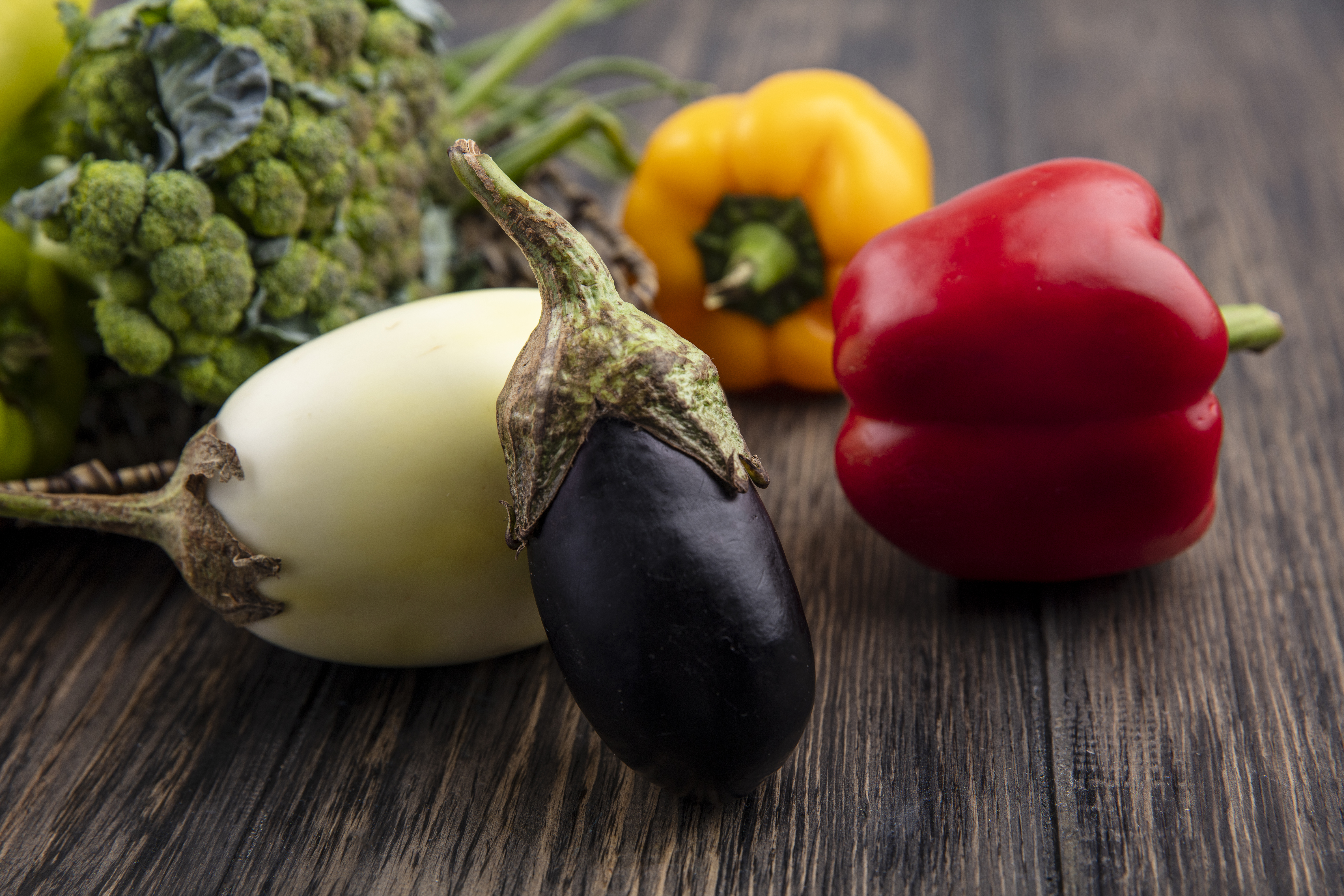 Eggplant and bell peppers sitting on a kitchen table