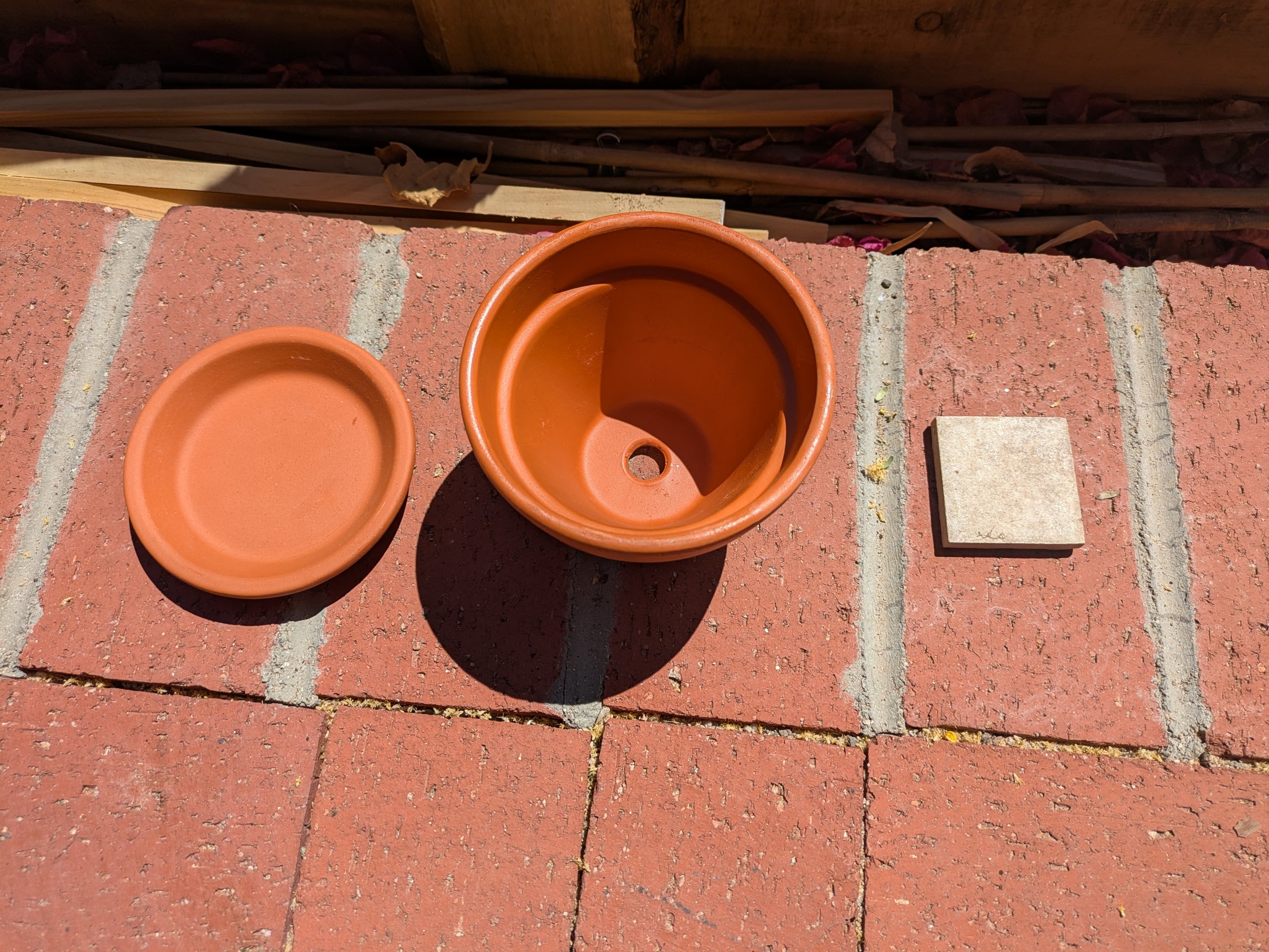 Teracotta plant pot with lid and piece of tile