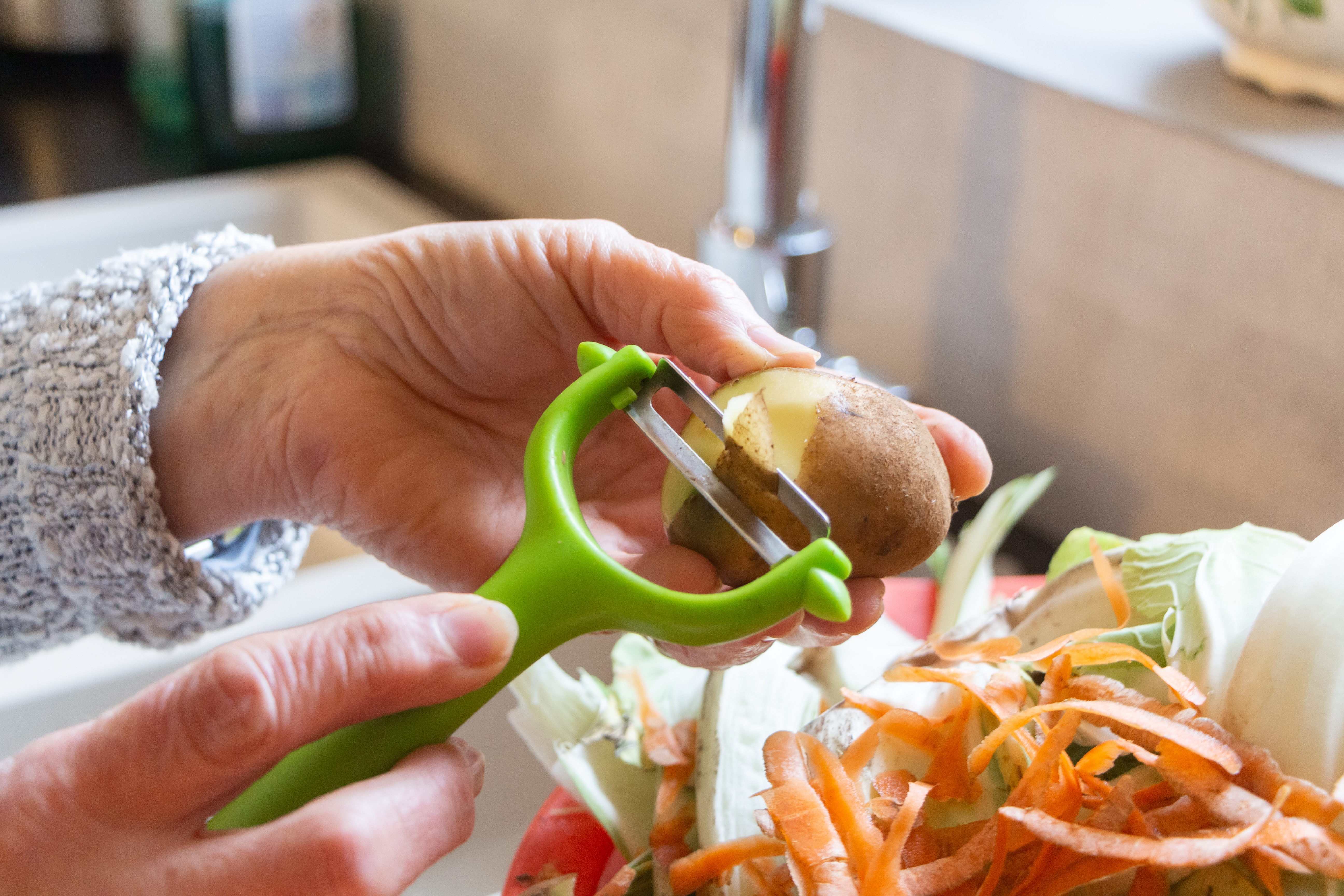 Person peeling vegetables and composting the scraps.