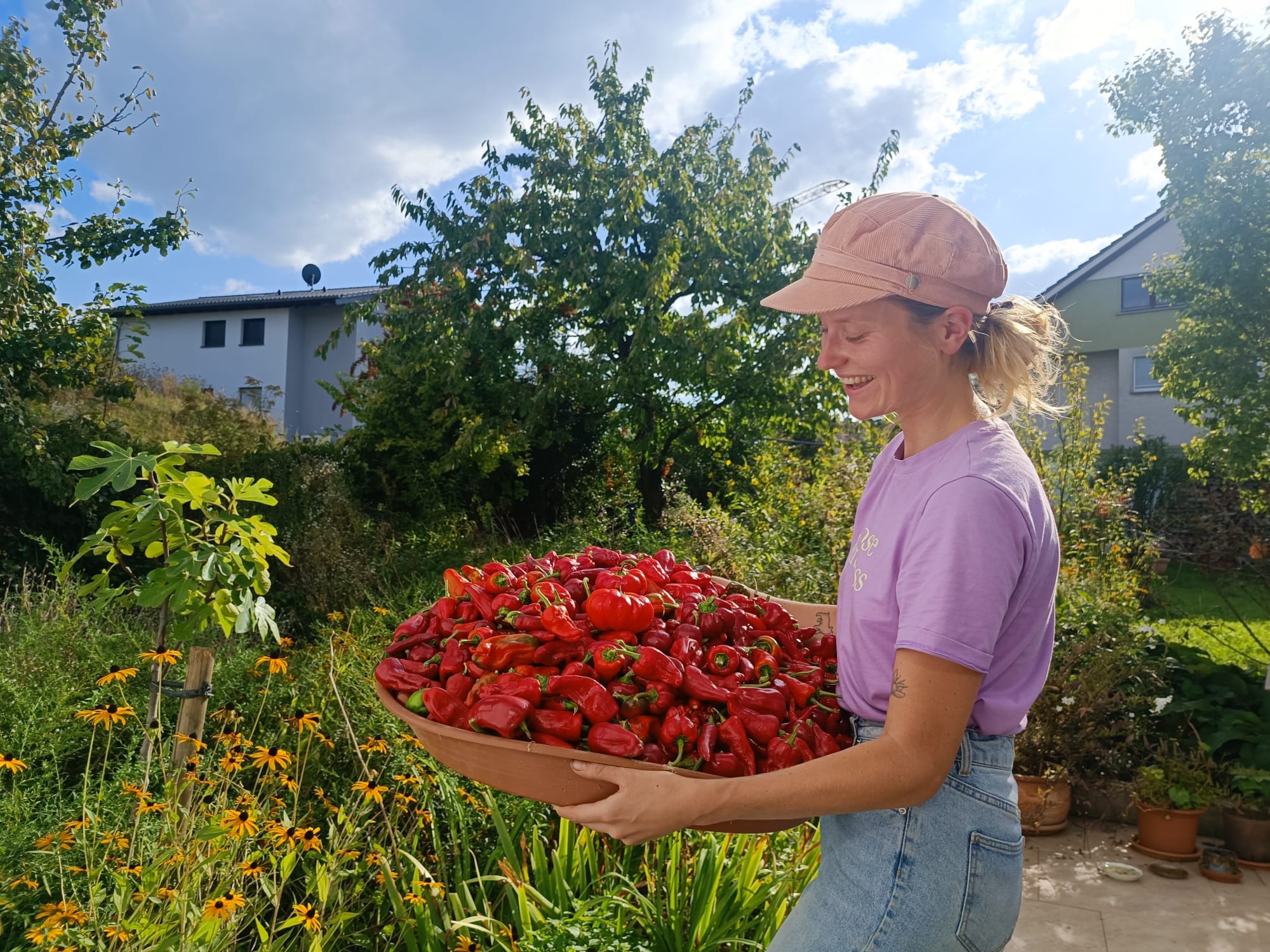 Woman holding a big basket overflowing of different varieties of red peppers. 