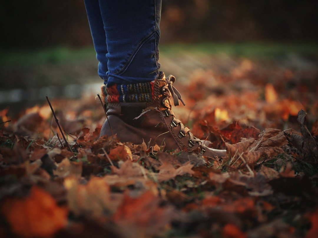 A person wearing boots standing in fallen leaves