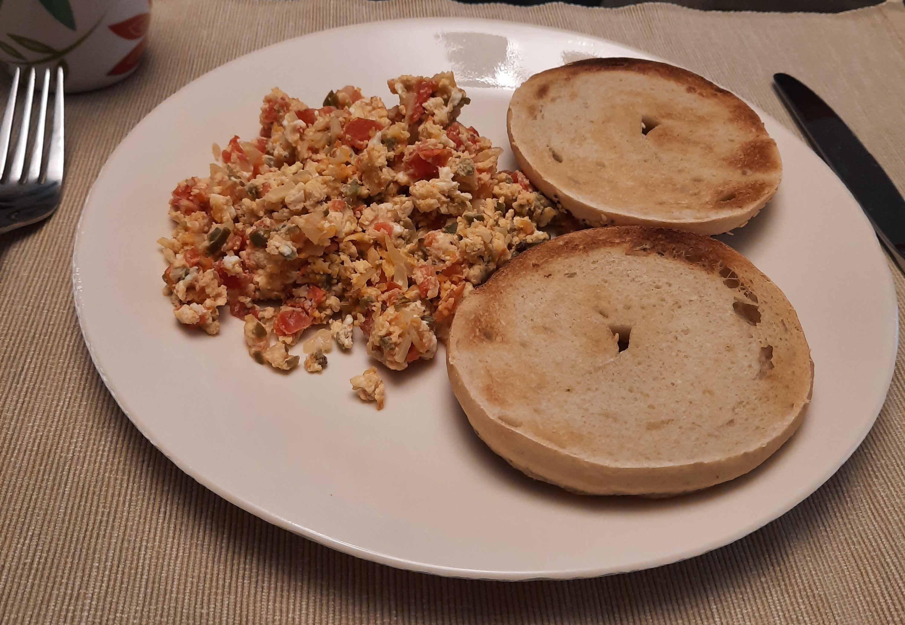 Mexican-style eggs on a plate with a toasted bagel