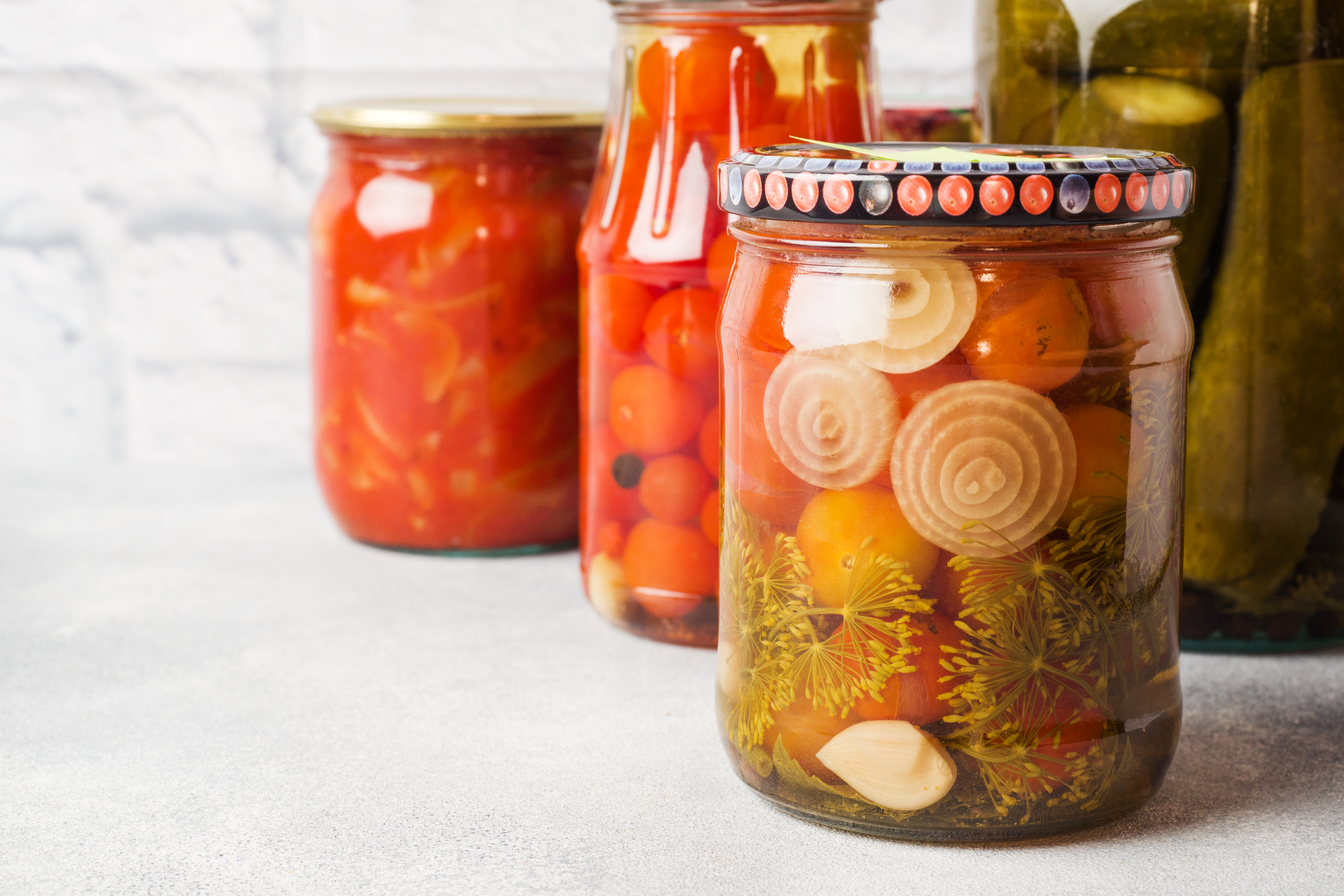 Various preserved vegetables in glass jars on a white background
